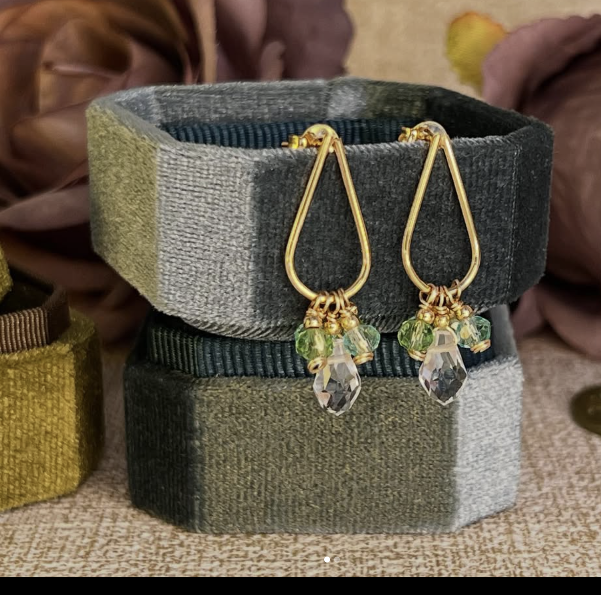 Aros Calissa con forma de gota dorada y detalles verdes y transparentes